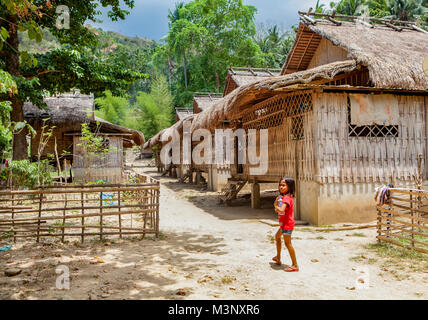 Un giovane Indigeni filippini Mangyan ragazza cammina per la sua casa nel villaggio di Talipanan con la sua acqua in bottiglia. Oriental Mindoro, Filippine. Foto Stock