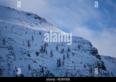 Gli ultimi raggi di sole su una ripida e coperta di neve pendio di montagna dell'Austria Foto Stock