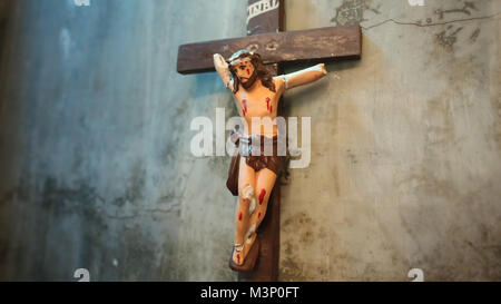 Il vecchio e il Broken crocifiggere Cristo appeso sul vecchio muro. Foto Stock