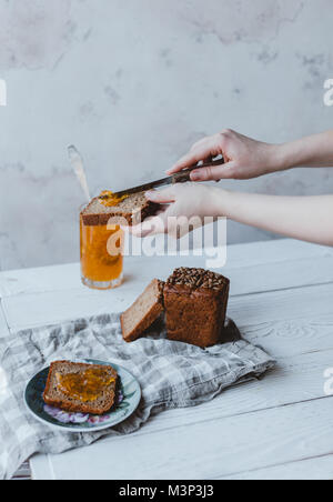 Vista parziale di donna mettendo inceppata sul pezzo di pane Foto Stock