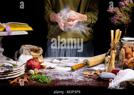 Vista parziale di mani umane preparazione impasto al tavolo con gli ingredienti Foto Stock