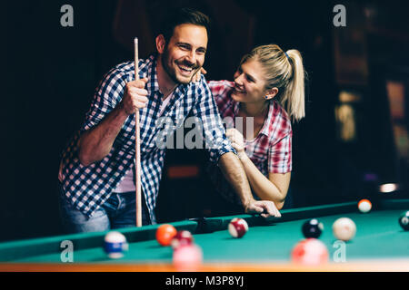 Coppia giovane giocare biliardo insieme in bar Foto Stock