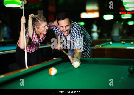 Coppia giovane giocare biliardo insieme in bar Foto Stock