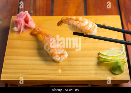 Close up di bastoncini prendendo parte del rotolo di sushi sul tavolo ristorante Foto Stock