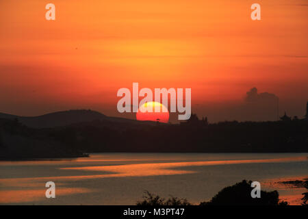 Alba sul lago. La mattina presto del paesaggio. la nebbia sull'acqua, foresta sagome e i raggi del sole nascente. Foto Stock