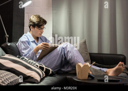 Ragazzo lettura Prenota in pigiama Foto Stock