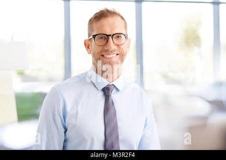 Ritratto di felice medio di età compresa tra i proprietari di indossare camicia e cravatta mentre in piedi presso l'ufficio. Foto Stock