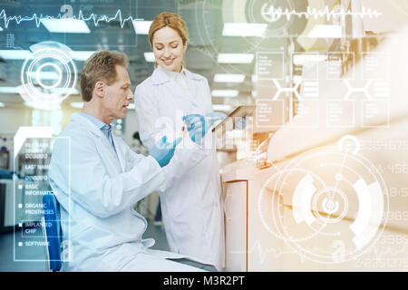 Grave medico tenendo un tubo di prova mentre il suo collega lo sta guardando Foto Stock