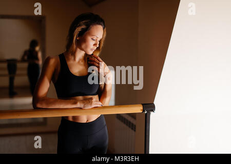 Donna ballerina in posa vicino a barre nel balletto studio Foto Stock