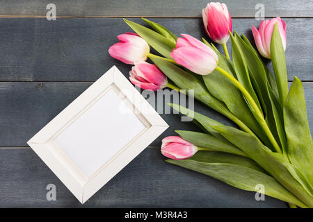Womens giorno. Tulipani rosa bouquet e un bianco vuoto sul telaio in legno di colore blu, sfondo spazio copia, vista dall'alto Foto Stock