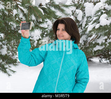 Una donna sta compiendo un salfi in un bosco innevato Foto Stock