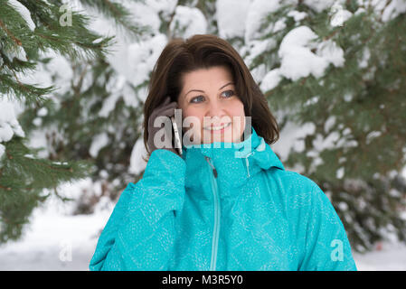 Donna che parla al telefono in un parco invernale Foto Stock