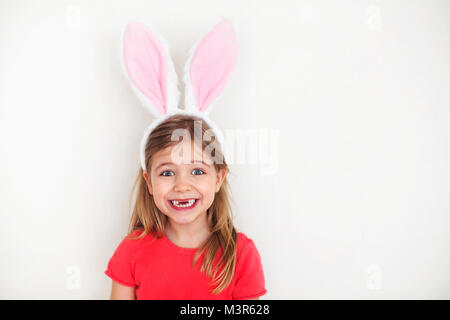 Felice dente perduto bambina indossa divertenti orecchie di coniglietto Foto Stock