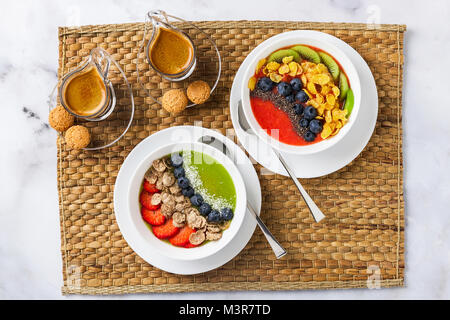 Due ciotole con diversi ottimi frullati da fragole e kiwi, con cereali per una colazione sana e bacche, chia semi e scaglie di noce di cocco con fre Foto Stock