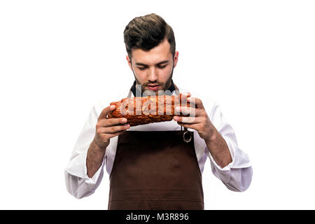 Giovane uomo aspetto modello vestito in ches grembiule dell'odore fresco pastrami isolati su sfondo bianco Foto Stock