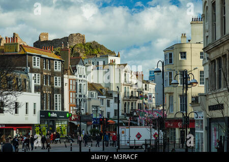 Hastings city centre, East Sussex, Inghilterra. Le rovine del castello sul colle in background. Foto Stock