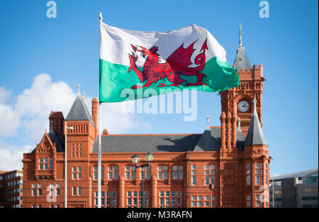 Una bandiera del Galles vola contro un cielo blu di fronte all'Edificio Pierhead a Cardiff Bay in una giornata di sole a Cardiff, nel Galles del Sud. Foto Stock