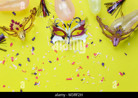 Table top visualizza immagine aerea di bella colorata maschera di Carnevale sfondo.piatto accessorio laici oggetto sulla moderna carta gialla a home office desk studio Foto Stock