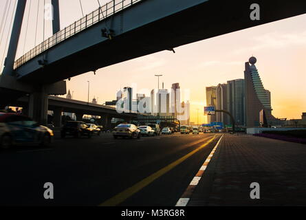 Dubai, Emirati Arabi Uniti, 11 Febbraio 2018: Dubai street scene con costantemente viva traffico con la nuova città vista al tramonto Foto Stock