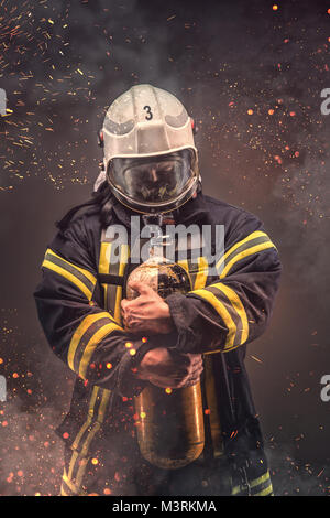 Vigile del fuoco in casco e maschera contiene i serbatoi di ossigeno. Foto Stock