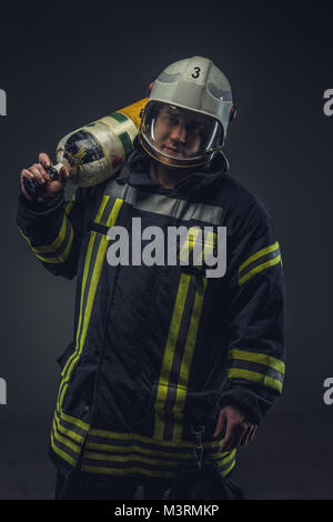 Vigile del fuoco nel casco detiene il serbatoio di ossigeno. Foto Stock