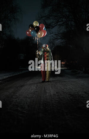 Immagine del clown con sfere in mani di notte sulla strada Foto Stock