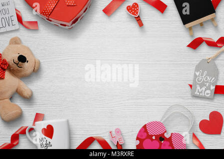 Regali per gli amanti di un bianco sullo sfondo di legno con spazio libero per il testo. Doni, tazze, clip, Teddy bear, iscrizioni. Vista dall'alto. Foto Stock