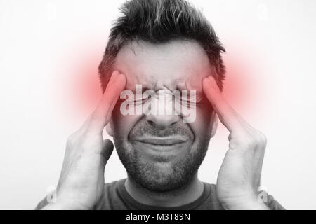 Caucasain uomo con mal di testa su sfondo bianco vicino la foto in bianco e nero con un cerchio rosso Foto Stock