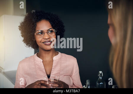 Due sorridente imprenditrici avente una conversazione mentre prendendo una pausa insieme in un ufficio moderno Foto Stock