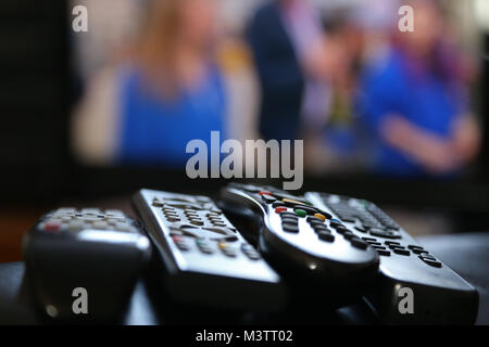 Una gamma di telecomandi per la televisione, satellite, DVD e sistema audio, sul braccio di una sedia, in Peterborough, CAMBRIDGESHIRE, febbraio 12, 20 Foto Stock
