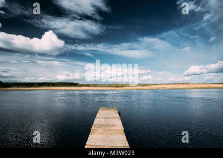 In legno antico molo di schede sulle calme acque del lago o fiume di sera o di mattina tempo. Bosco su altro lato. Paesaggio. La natura dello sfondo. Foto Stock