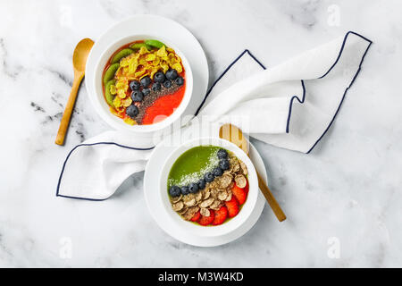 Due ciotole con diversi ottimi frullati da fragole e kiwi, con cereali per una colazione sana e bacche, chia semi e scaglie di noce di cocco con fre Foto Stock