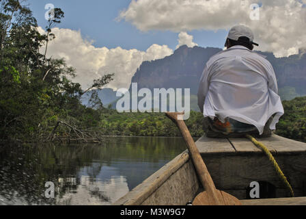 Un uomo che indossa una camicia bianca in seduta sulla prua di un motoscafo viaggia su un fiume in Venezuela Foto Stock