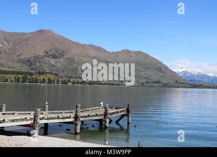 Visualizzare passato un pontile in legno cercando attraverso Roys baia a sud del Lago Wanaka, Otago, South Island, in Nuova Zelanda. Foto Stock