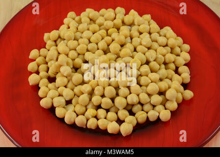 Conserve di ceci o di ceci, lavati e sgocciolati e riversato sulla targhetta rossa come preparazione per essere utilizzato come ingrediente in insalata o un pasto Foto Stock