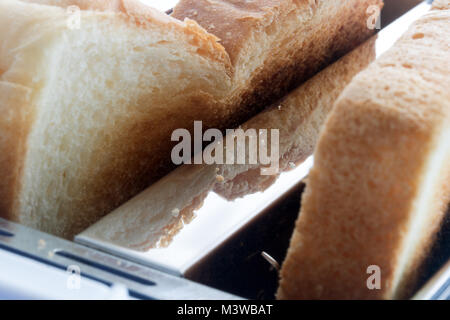 Tostare in un tostapane. Toast fritti fette all'interno del tostapane. Una vista ravvicinata di pasticceria in un dispositivo di tostatura. Foto Stock