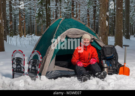 Felice turista attivo si trova nella foresta di inverno in tenda Foto Stock