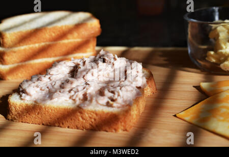 Tonno Insalata di pesce spalmato sul pane bianco faccia aperta stile, con burro nella ciotola di vetro e bianco e giallo le fette di formaggio Foto Stock