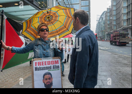 Un uomo racconta di un manifestante tenendo una bandiera palestinese banner che ella è contro gli ebrei. Lei dice di lui che la protesta non è contro gli ebrei ma contro il modo in cui i governi israeliani trattare palestinese e che lei è un ebreo. Foto Stock