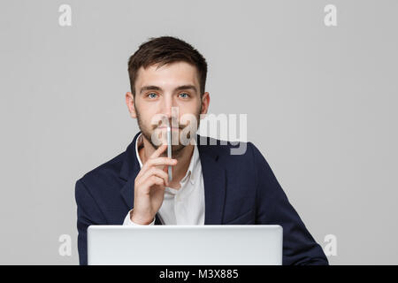 Il concetto di business - Ritratto bello bello Happy business man in tuta la riproduzione telefono mobili e sorridente con notebook a lavorare in ufficio. Sfondo bianco. Foto Stock