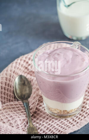 Mirtillo yogurt naturale fiocchi di avena granola diversi strati in un bicchiere Foto Stock