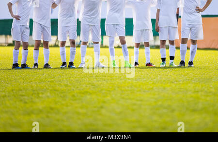 Youth Football Team. Giovani Calciatori in piedi in fila. Ragazzi in piedi insieme durante gli scatti di penalità. Ragazzi in bianco Soccer Jersey camicie Foto Stock