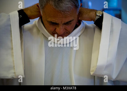 Cappellano in pensione (Lt. Col.) Robert Bruno regola il suo bianco alb prima di entrare nel dormitorio cappella per la preghiera del mattino. Il camice è la veste comune per tutti i ministri a Messa. (U.S. Air Force foto/Staff Sgt. Andrew Lee) 141105-F-NL936-114 da AirmanMagazine Foto Stock