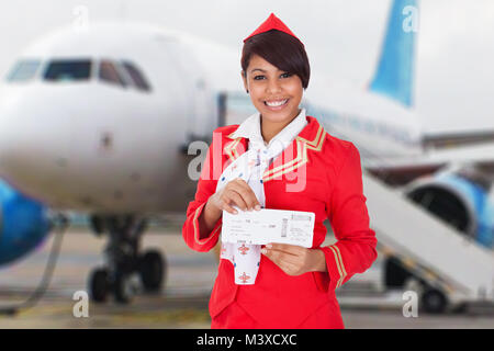 Ritratto di un giovane sorridenti hostess nella parte anteriore del velivolo Foto Stock