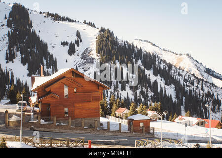 Casa di legno naturale in montagna. Villa sul pendio di una collina verde con alberi di Natale nella neve d'inverno. Il centro ricreativo sulle Highlands. Foto Stock