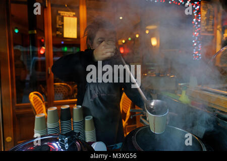 In un freddo giorno di inverno, una donna in vendita di vino caldo e sidro da una posizione al di fuori di un ristorante sull'Ile de la Cité a Parigi. Foto Stock