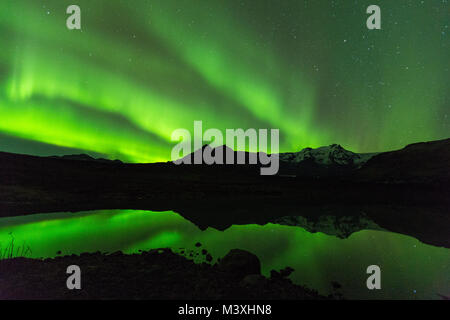 Green aurora luce dietro il lago di montagna in Islanda Europa al parco nazionale di skaftafell Foto Stock
