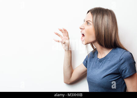 Chiudere isolata Ritratto di giovane arrabbiato arrabbiato donna tenendo le mani nel gesto furioso. Giovane donna con capelli biondi in blu T-shirt. Huma negativa Foto Stock