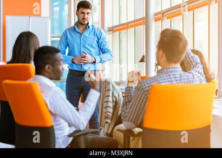 Gruppo di casualmente vestito imprenditori discutere le idee in ufficio. Foto Stock