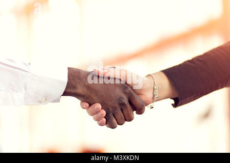 Primo piano del bianco e nero si stringono la mano su una trattativa Foto Stock